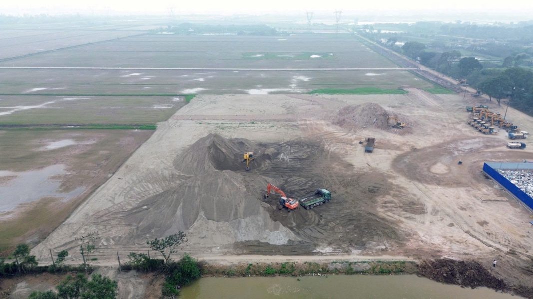 Máy xúc và xe tải hoạt động liên tục tại khu vực san lấp mặt bằng, đánh dấu giai đoạn khởi động thi công nền móng Sân vận động Trống Đồng.